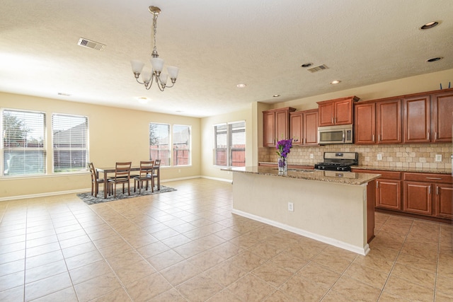 13018 Foxwood Creek Ln, Houston, TX 77044 - kitchen featuring appliances with stainless steel finishes, light tile patterned flooring, decorative backsplash, an island with sink, and a textured ceiling