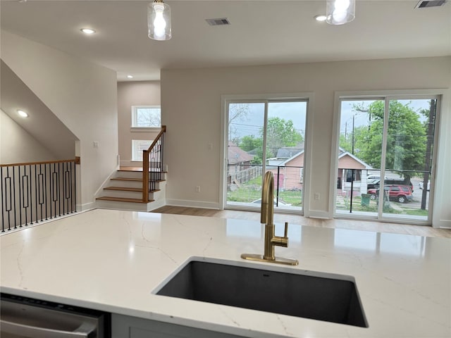 1307 71st St Unit A, Houston, TX 77011 - kitchen featuring stainless steel dishwasher, recessed lighting, light stone counters, decorative light fixtures, and wood finished floors