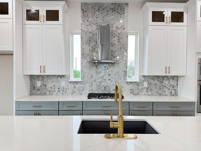 1307 71st St Unit A, Houston, TX 77011 - kitchen featuring wall chimney range hood, tasteful backsplash, glass insert cabinets, and gray cabinets