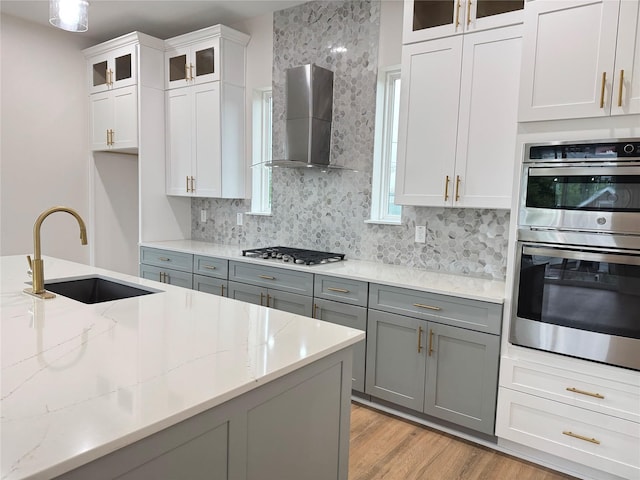 1307 71st St Unit A, Houston, TX 77011 - kitchen with wall chimney exhaust hood, stainless steel appliances, gray cabinets, and decorative backsplash