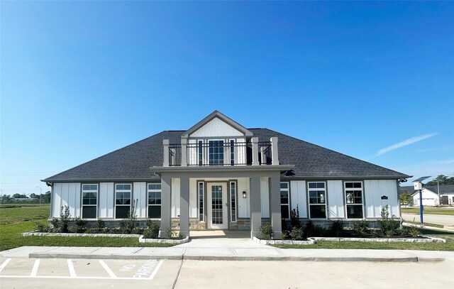1214 Hidden Oaks Dr, Tomball, TX 77375 - view of front facade with a balcony, roof with shingles, board and batten siding, and a porch
