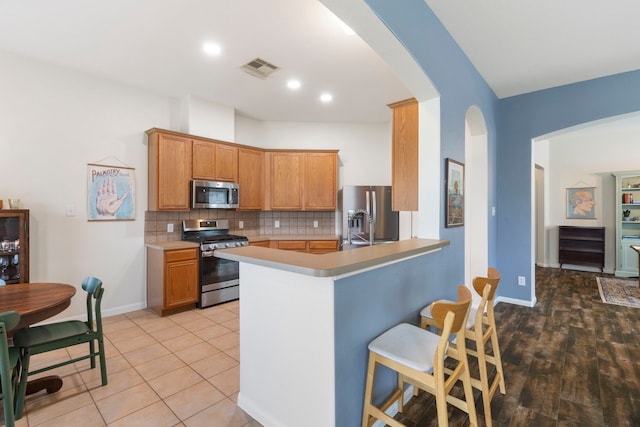 4613 Meridian Park Dr, Pearland, TX 77584 - kitchen with stainless steel appliances, arched walkways, tasteful backsplash, a breakfast bar area, and light countertops