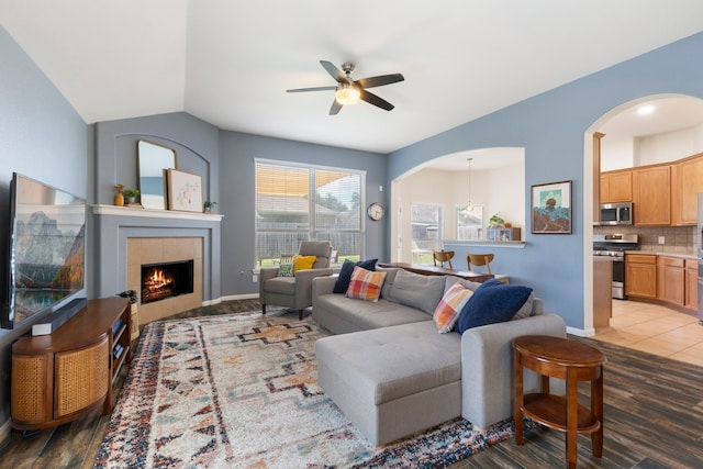 4613 Meridian Park Dr, Pearland, TX 77584 - living room featuring arched walkways, a ceiling fan, a tiled fireplace, wood finished floors, and lofted ceiling