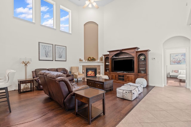 24914 Hazel Ranch Dr, Katy, TX 77494 - living area featuring arched walkways, a towering ceiling, a glass covered fireplace, ceiling fan, and wood finished floors