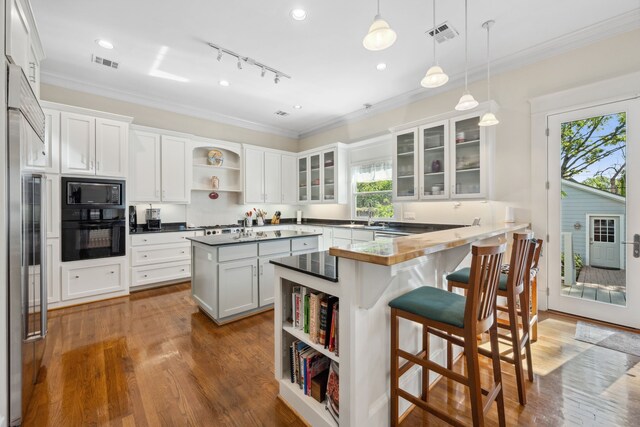 940 Columbia St, Houston, TX 77008 - kitchen with open shelves, black appliances, a kitchen breakfast bar, dark countertops, and a peninsula