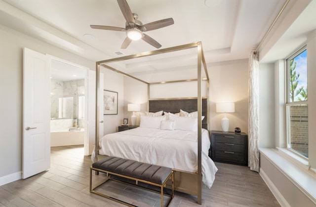 19318 Stagecoach Breeze Ln, Tomball, TX 77377 - bedroom featuring light wood finished floors, connected bathroom, baseboards, a raised ceiling, and ceiling fan