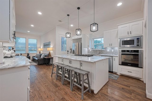 1035 Herkimer St, Houston, TX 77008 - kitchen with stainless steel appliances, ornamental molding, white cabinets, a center island, and a kitchen breakfast bar