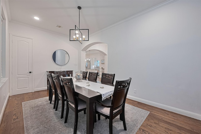 1035 Herkimer St, Houston, TX 77008 - dining space with arched walkways, crown molding, baseboards, wood finished floors, and a chandelier