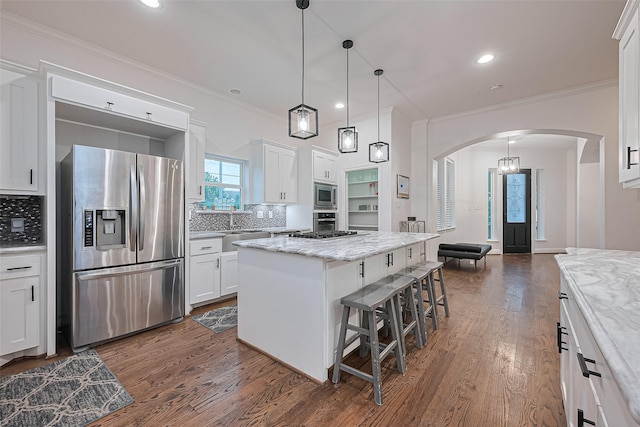 1035 Herkimer St, Houston, TX 77008 - kitchen featuring stainless steel appliances, arched walkways, a kitchen island, a breakfast bar area, and decorative backsplash