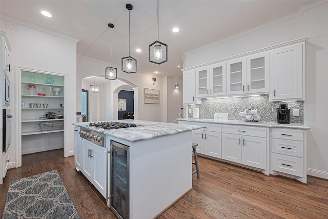 1035 Herkimer St, Houston, TX 77008 - kitchen featuring arched walkways, stainless steel appliances, beverage cooler, crown molding, and white cabinets