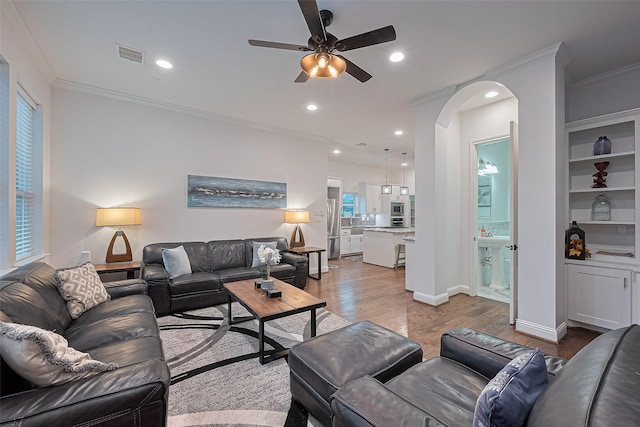 1035 Herkimer St, Houston, TX 77008 - living room with ornamental molding, a ceiling fan, light wood finished floors, arched walkways, and recessed lighting
