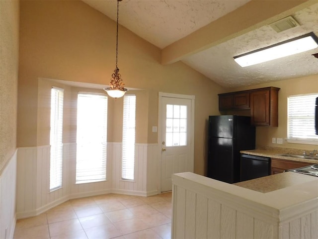 17002 Rippling Mill Dr, Sugar Land, TX 77498 - kitchen with black appliances, wainscoting, light countertops, light tile patterned floors, and decorative light fixtures
