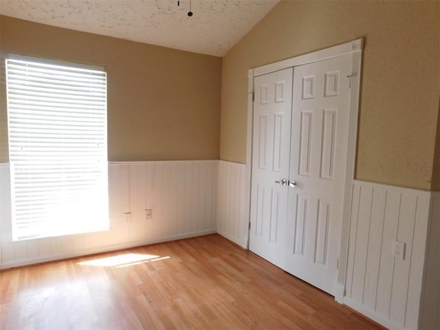 17002 Rippling Mill Dr, Sugar Land, TX 77498 - unfurnished bedroom with a wainscoted wall, vaulted ceiling, light wood-type flooring, and a closet