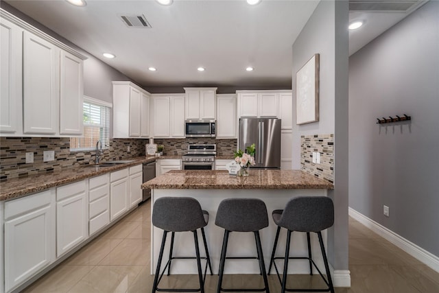 14619 Sanour Dr, Houston, TX 77084 - kitchen featuring stainless steel appliances, a sink, a kitchen bar, white cabinets, and stone countertops