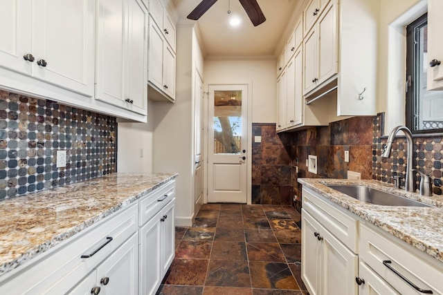 4922 Linden St, Bellaire, TX 77401 - kitchen with a sink, ceiling fan, light stone counters, crown molding, and decorative backsplash