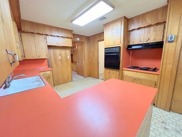302 Cordell Dr, Crockett, TX 75835 - kitchen with black appliances, a sink, under cabinet range hood, wood walls, and light countertops