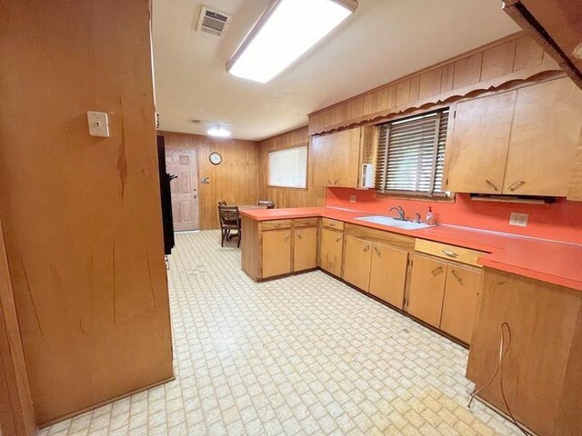 302 Cordell Dr, Crockett, TX 75835 - kitchen with a sink, a peninsula, light countertops, and wooden walls