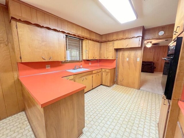 302 Cordell Dr, Crockett, TX 75835 - kitchen with a sink, oven, a peninsula, wood walls, and light countertops