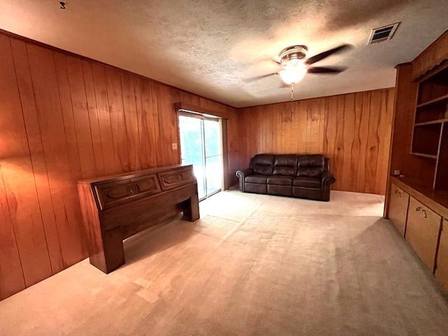 302 Cordell Dr, Crockett, TX 75835 - living area with wood walls, ceiling fan, carpet flooring, and a textured ceiling