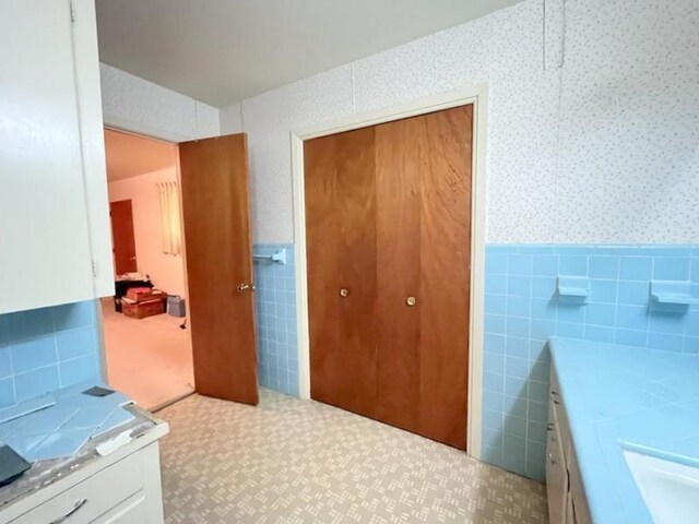 302 Cordell Dr, Crockett, TX 75835 - bathroom featuring wainscoting, tile walls, wallpapered walls, and vanity