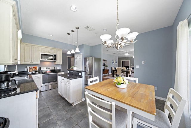 3525 N Morning Glory Dr, Santa Fe, TX 77517 - kitchen with stainless steel appliances, a chandelier, cream cabinets, a kitchen island, and dark tile patterned flooring