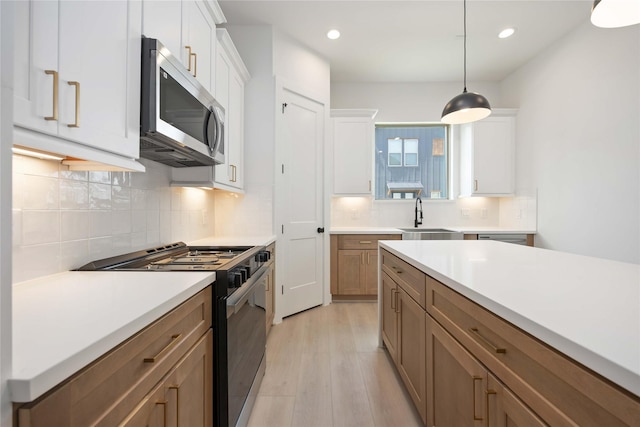 1941 Johanna Dr, Houston, TX 77055 - kitchen featuring stainless steel microwave, black stove, a sink, light wood finished floors, and light countertops