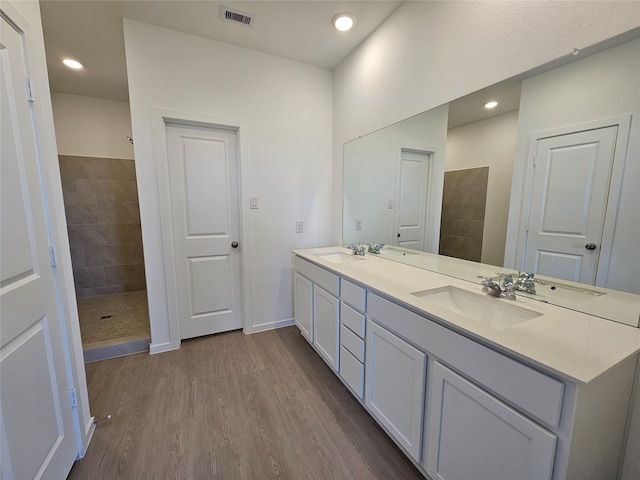 10623 Autumn Trace Dr, Beasley, TX 77417 - full bathroom with double vanity, a tile shower, wood finished floors, and baseboards