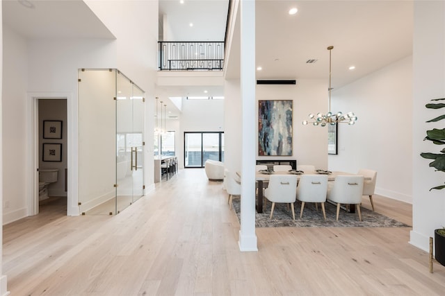 5008 Holt St, Bellaire, TX 77401 - dining area with light wood-type flooring, a chandelier, baseboards, a towering ceiling, and recessed lighting