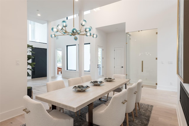 5008 Holt St, Bellaire, TX 77401 - dining space with a chandelier, light wood finished floors, a high ceiling, and baseboards