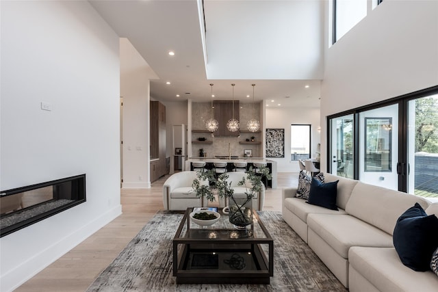 5008 Holt St, Bellaire, TX 77401 - living area featuring light wood-type flooring, a high ceiling, recessed lighting, and baseboards