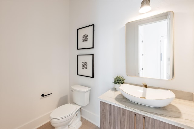 5008 Holt St, Bellaire, TX 77401 - half bathroom with baseboards, toilet, vanity, and wood finished floors