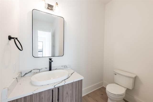 5008 Holt St, Bellaire, TX 77401 - half bathroom featuring vanity, toilet, wood finished floors, and baseboards