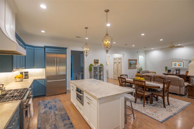 10614 Moonlight Dr, Houston, TX 77096 - kitchen with high end appliances, extractor fan, blue cabinetry, open floor plan, and light countertops