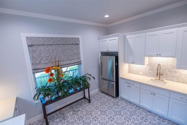 10614 Moonlight Dr, Houston, TX 77096 - kitchen featuring freestanding refrigerator, a sink, light countertops, white cabinets, and crown molding