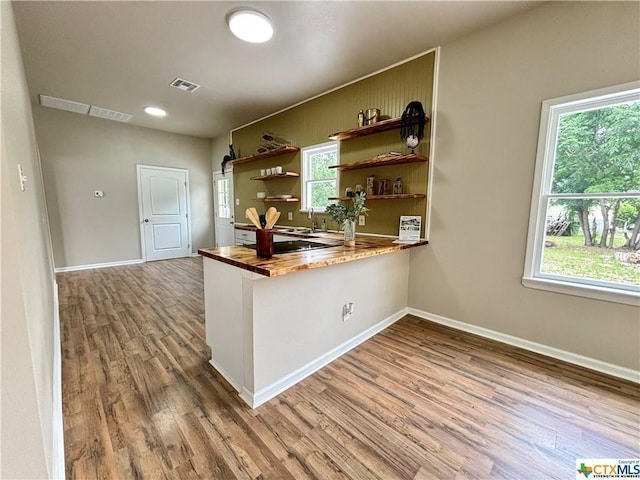 515 Mitchell Ave, Seguin, TX 78155 - kitchen featuring butcher block counters, wood finished floors, open shelves, a peninsula, and baseboards