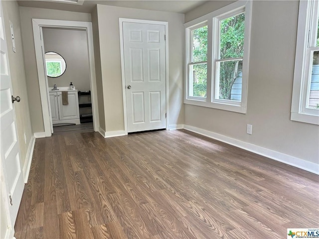 515 Mitchell Ave, Seguin, TX 78155 - unfurnished bedroom with dark wood-style flooring, multiple windows, and baseboards
