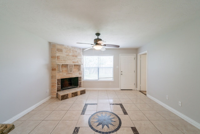 423 N Vista Dr, Houston, TX 77073 - unfurnished living room with ceiling fan, light tile patterned floors, a stone fireplace, baseboards, and a textured ceiling