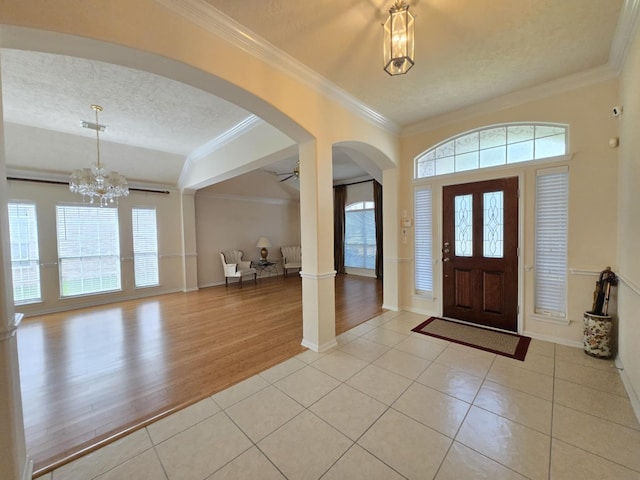 17427 N Riata Lake Dr, Cypress, TX 77433 - foyer entrance featuring arched walkways, healthy amount of natural light, ornamental molding, light tile patterned flooring, and a textured ceiling