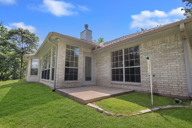 627 Shoreline Dr, Brookeland, TX 75931 - back of property with a patio, a yard, a chimney, and brick siding