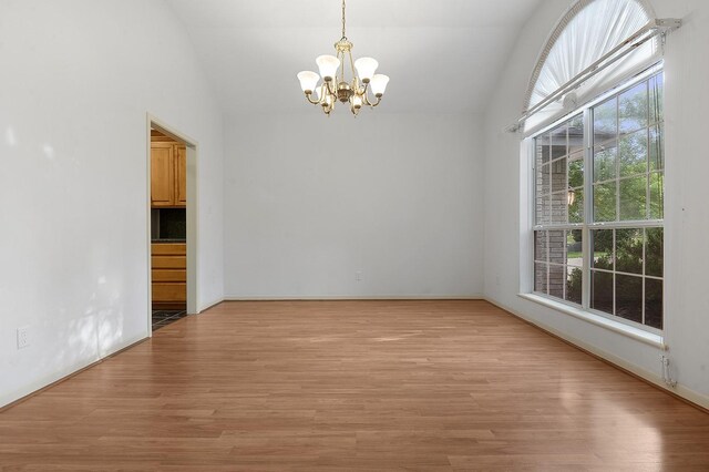 627 Shoreline Dr, Brookeland, TX 75931 - empty room with a chandelier, vaulted ceiling, light wood finished floors, and baseboards