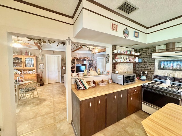 706 W St, Yoakum, TX 77995 - kitchen featuring white gas range, crown molding, a textured ceiling, stainless steel microwave, and dark brown cabinets