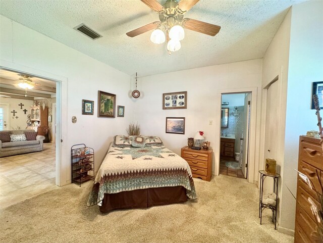 706 W St, Yoakum, TX 77995 - bedroom featuring light carpet, a textured ceiling, ensuite bathroom, and a ceiling fan