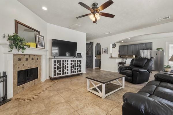 23706 River Place Dr, Katy, TX 77494 - living area with a ceiling fan, a tiled fireplace, light tile patterned floors, arched walkways, and recessed lighting