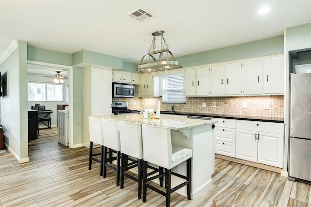 6915 Oak Bend Dr, Alvin, TX 77511 - kitchen with stainless steel appliances, decorative backsplash, light wood-type flooring, and white cabinetry