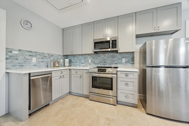 523 W 15th St, Houston, TX 77008 - kitchen featuring stainless steel appliances, gray cabinetry, light countertops, and decorative backsplash