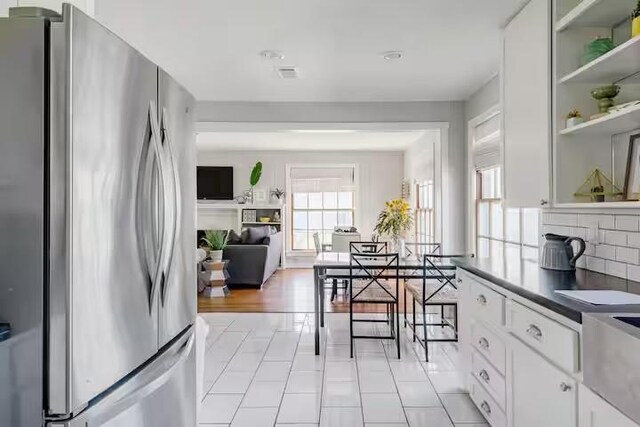 701 Gilchrist, College Station, TX 77840 - kitchen with freestanding refrigerator, white cabinets, backsplash, dark countertops, and light tile patterned flooring