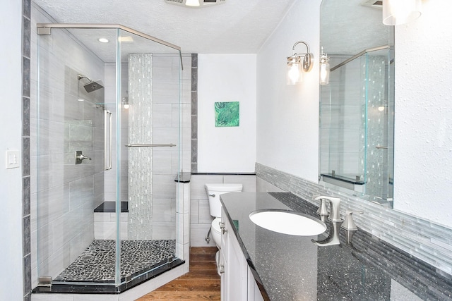 16323 Elmwood Point Ln, Sugar Land, TX 77498 - bathroom featuring a stall shower, vanity, toilet, a textured ceiling, and wood finished floors