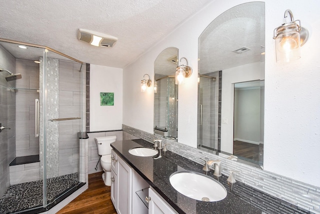 16323 Elmwood Point Ln, Sugar Land, TX 77498 - bathroom with toilet, a textured ceiling, double vanity, a shower stall, and wood finished floors