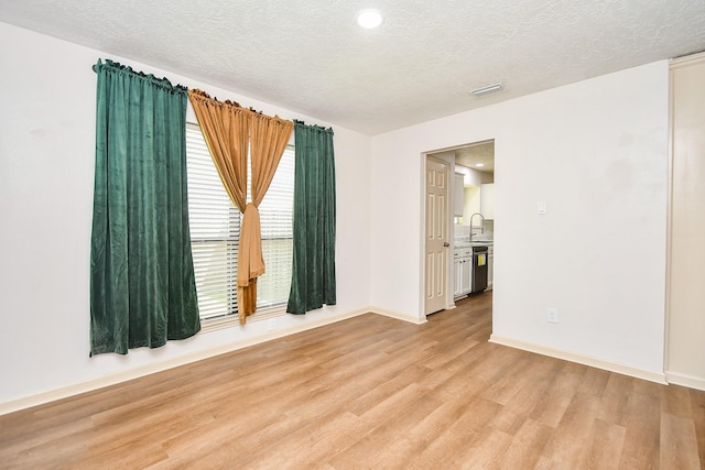 16323 Elmwood Point Ln, Sugar Land, TX 77498 - empty room with light wood-style floors, a sink, a textured ceiling, baseboards, and recessed lighting