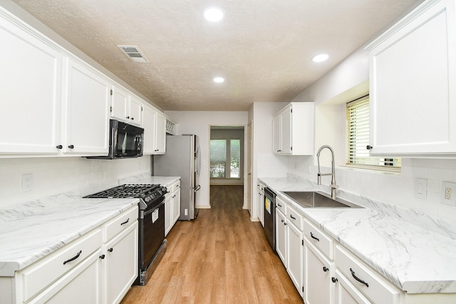 16323 Elmwood Point Ln, Sugar Land, TX 77498 - kitchen featuring black appliances, a sink, light wood-type flooring, white cabinetry, and recessed lighting
